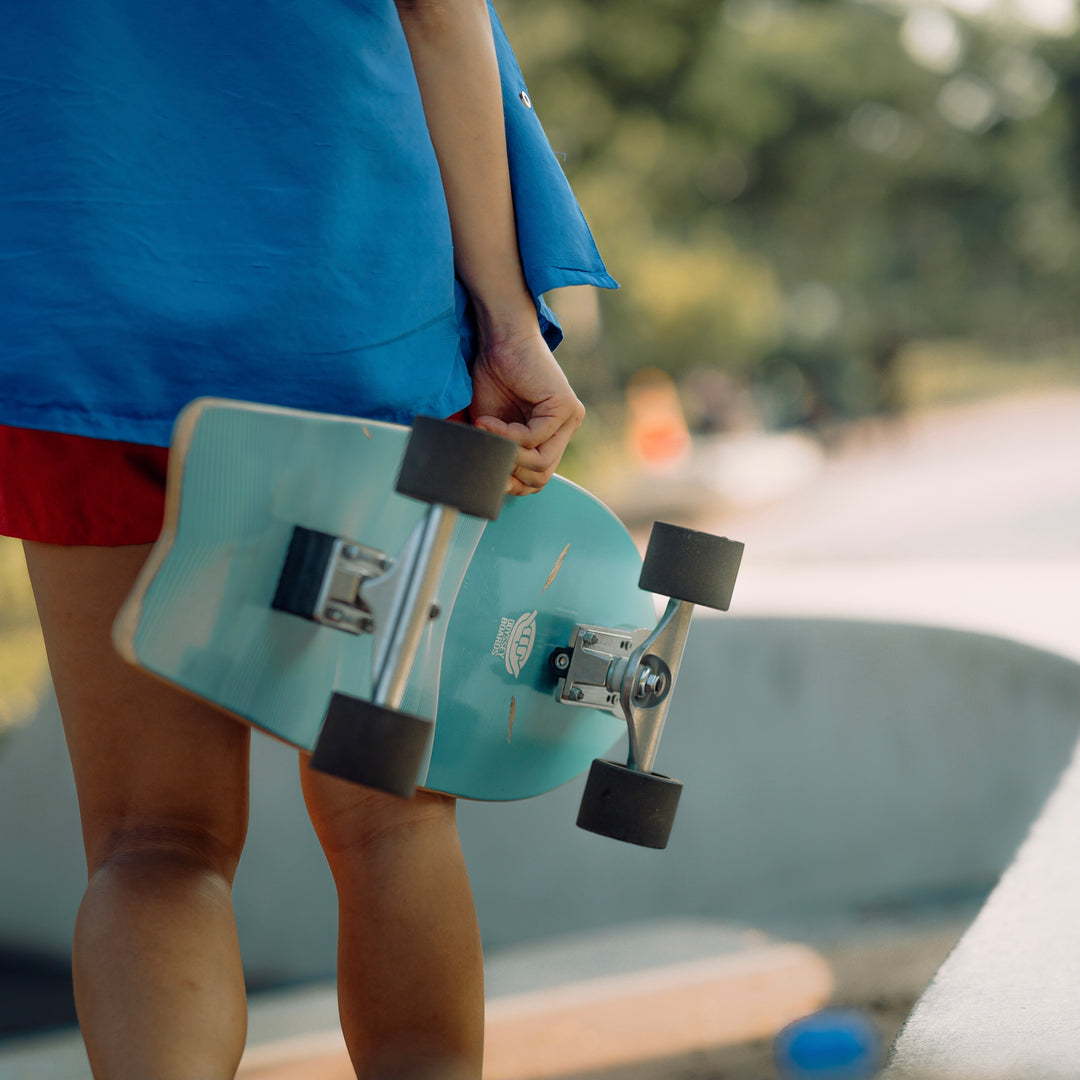 person holding blue surfskate with wave design